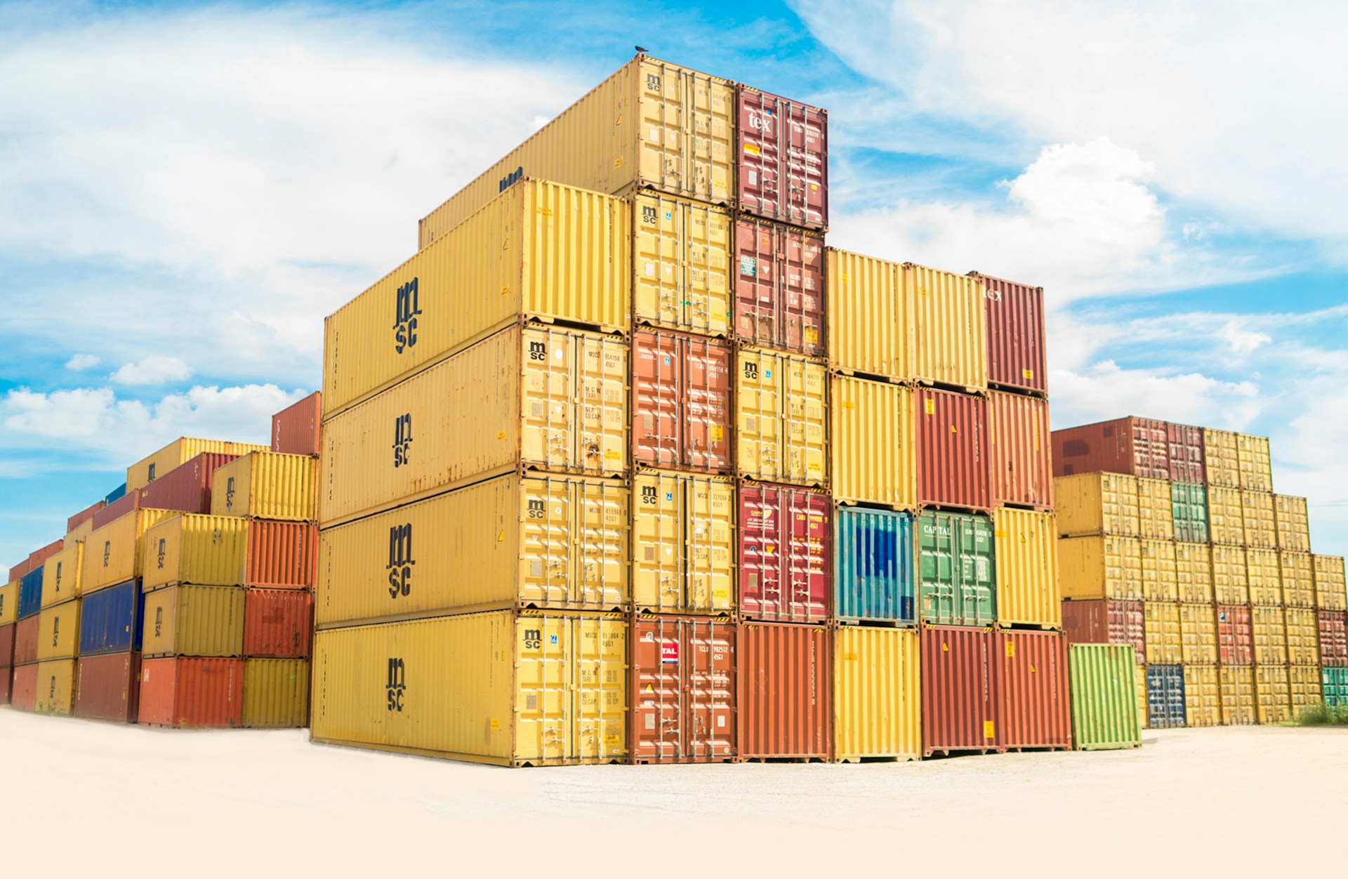Stacked yellow shipping containers at a terminal
